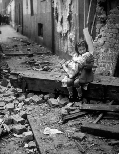 Малко момиче седи пред останките на разрушения си при бомбардировките дом. Лондон, 1940 година. 